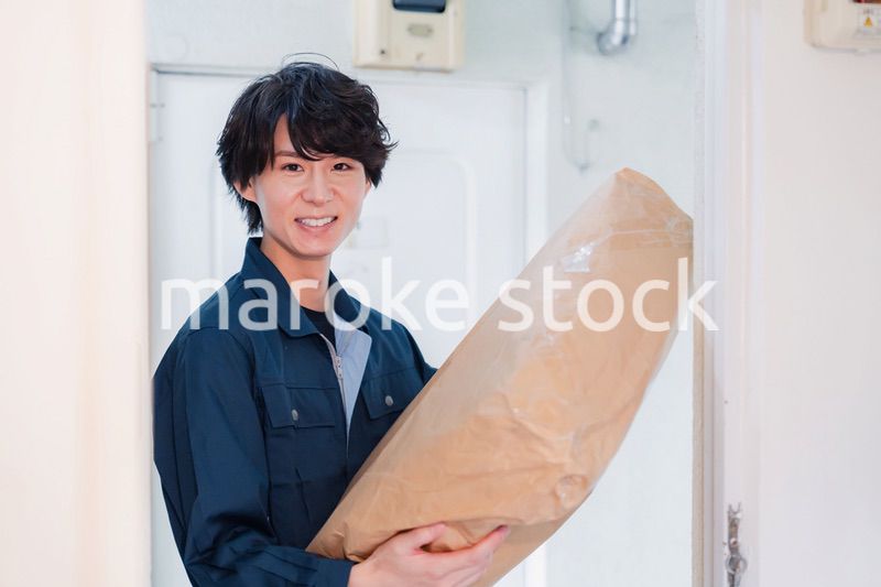 古いマンションに荷物を届ける男性