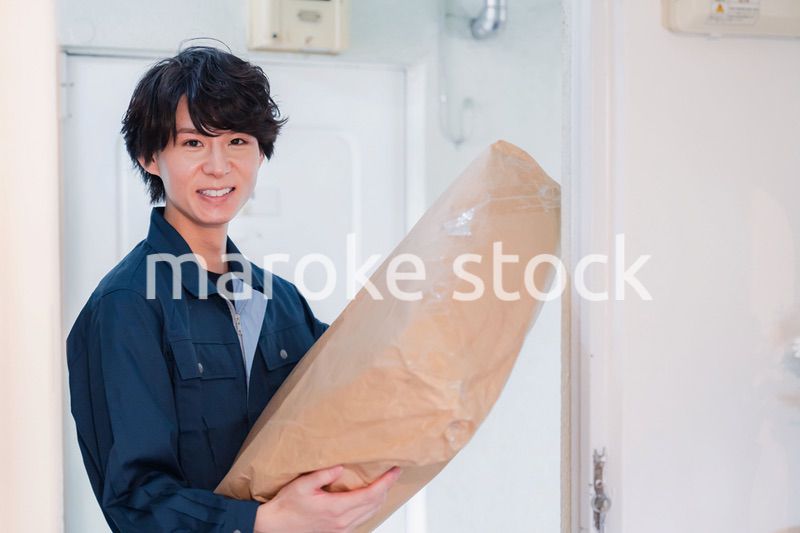 古いマンションに荷物を届ける男性
