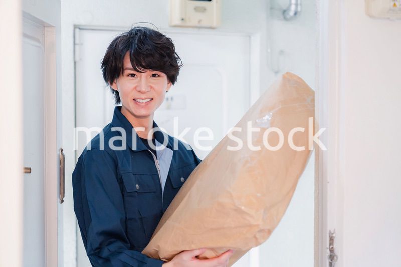 古いマンションに荷物を届ける男性