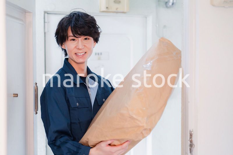 古いマンションに荷物を届ける男性