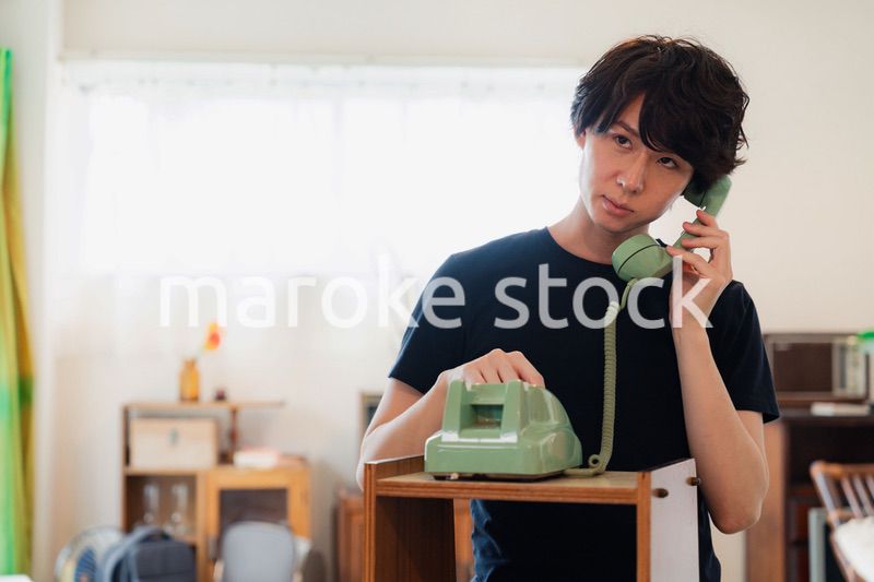 固定電話で電話をする若い男性