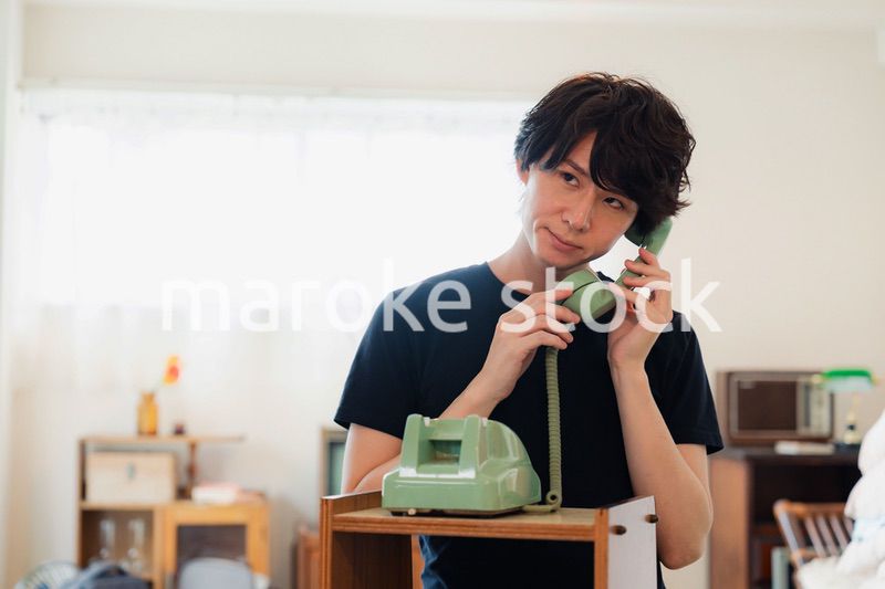 固定電話で電話をする若い男性