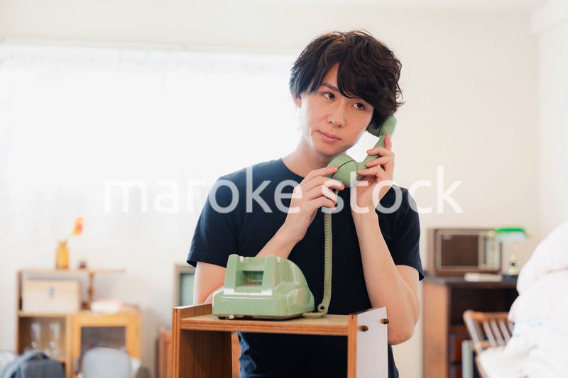 固定電話で電話をする若い男性