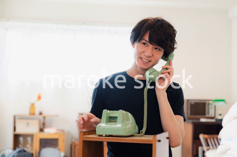 固定電話で電話をする若い男性