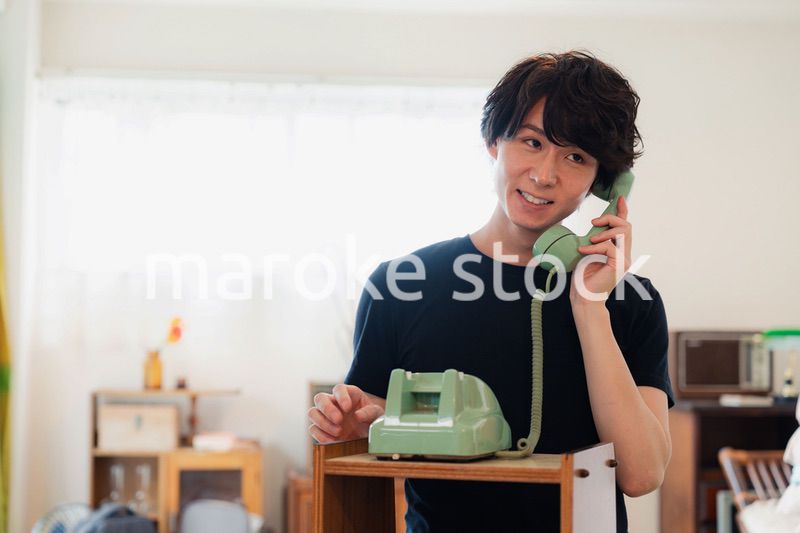 固定電話で電話をする若い男性