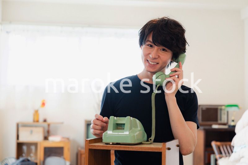 固定電話で電話をする若い男性