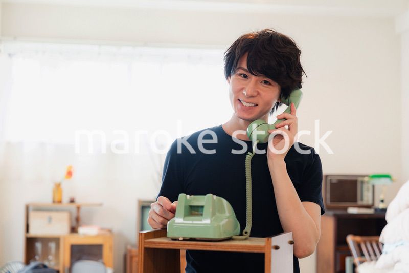 固定電話で電話をする若い男性