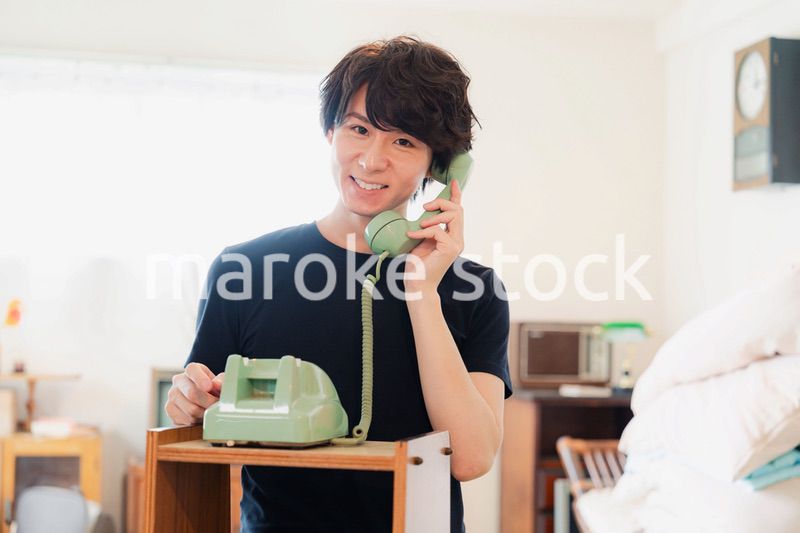 固定電話で電話をする若い男性