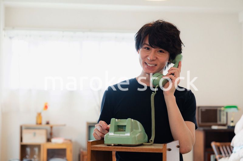 固定電話で電話をする若い男性