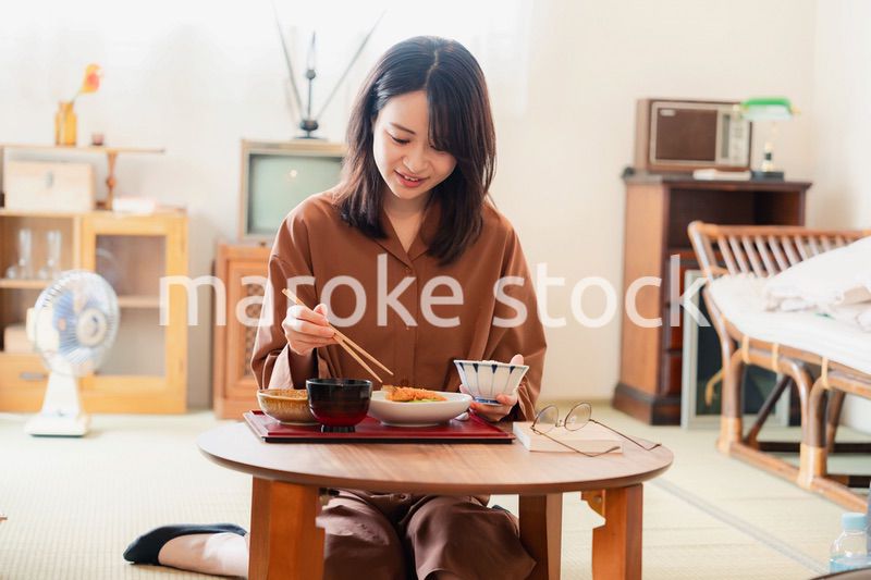 和室でご飯を食べる若い女性