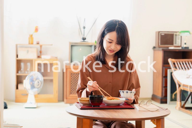 和室でご飯を食べる若い女性