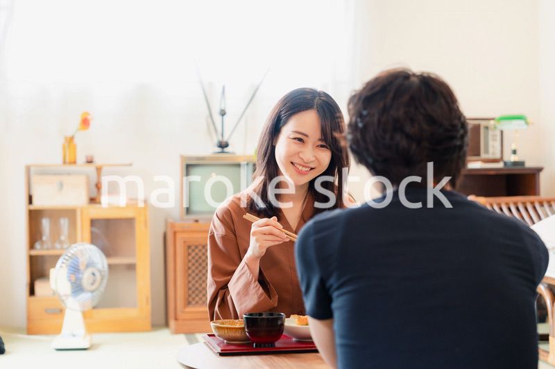 ドラマのようなレトロな雰囲気の食卓でごはんを食べる若い夫婦