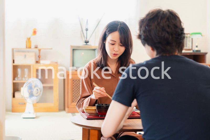 ドラマのようなレトロな雰囲気の食卓でごはんを食べる若い夫婦