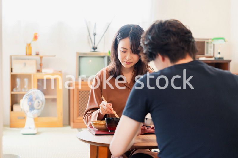 ドラマのようなレトロな雰囲気の食卓でごはんを食べる若い夫婦