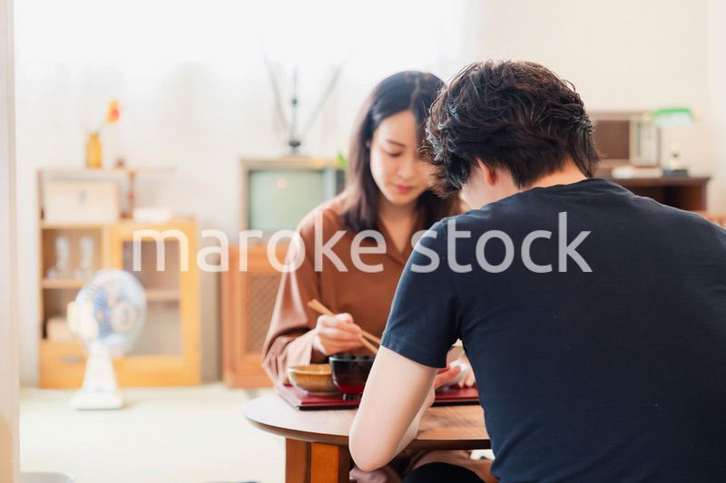 ドラマのようなレトロな雰囲気の食卓でごはんを食べる若い夫婦