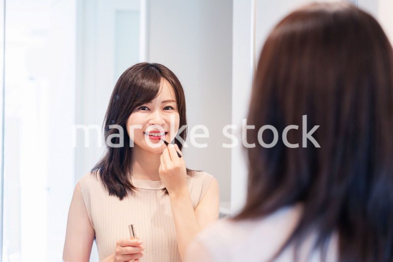 家でメイクをする若い女性