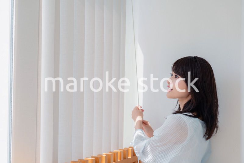 バーチカルブラインドを使う若い女性