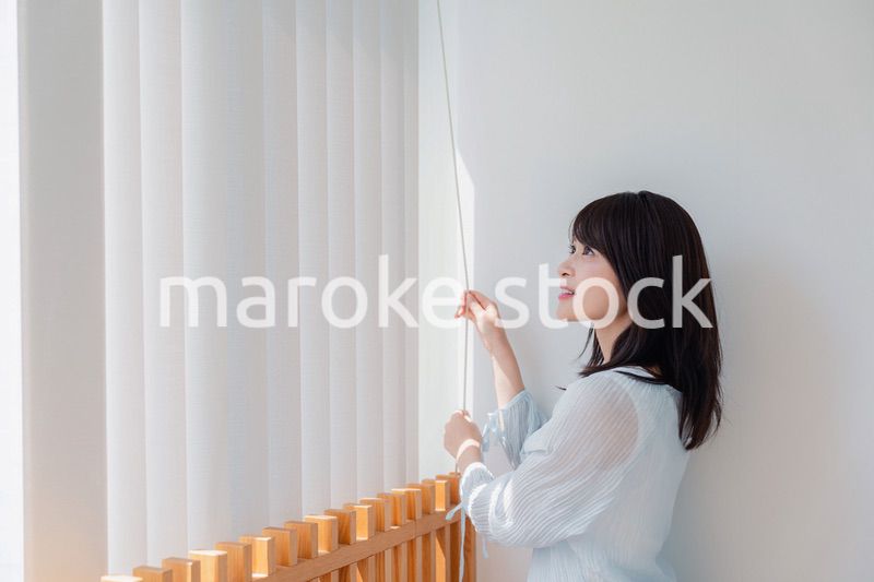 バーチカルブラインドを使う若い女性