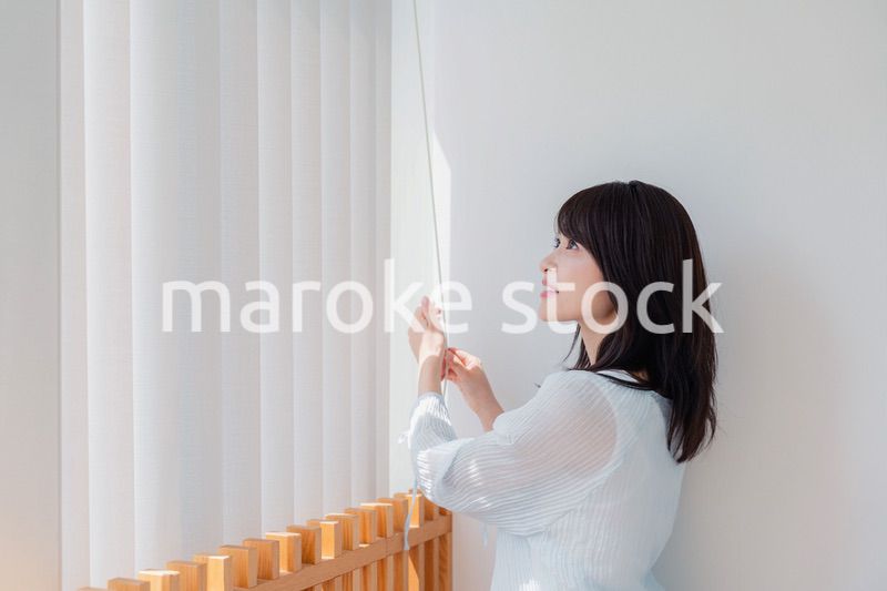 バーチカルブラインドを使う若い女性