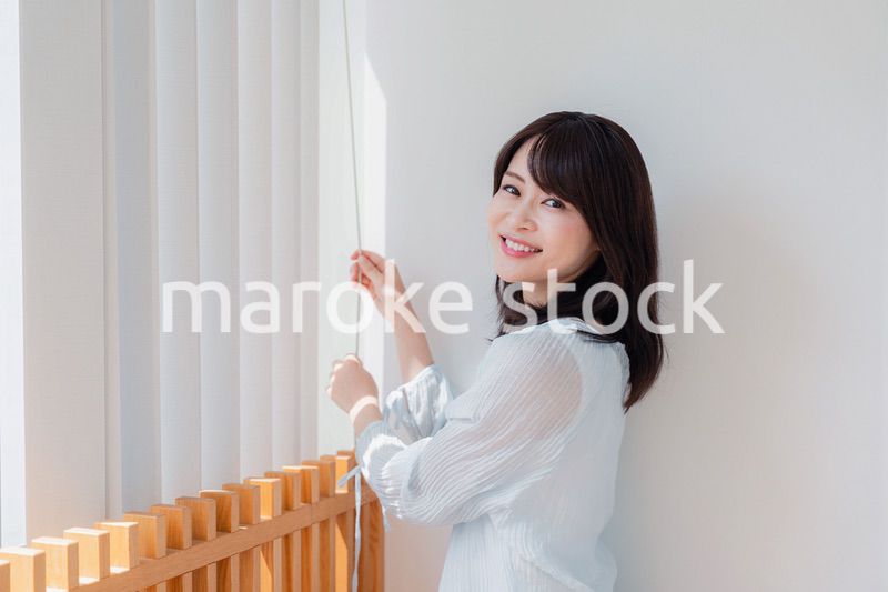 バーチカルブラインドを使う若い女性