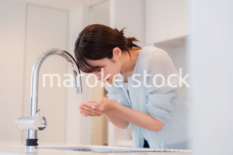 家で洗顔をする若い女性