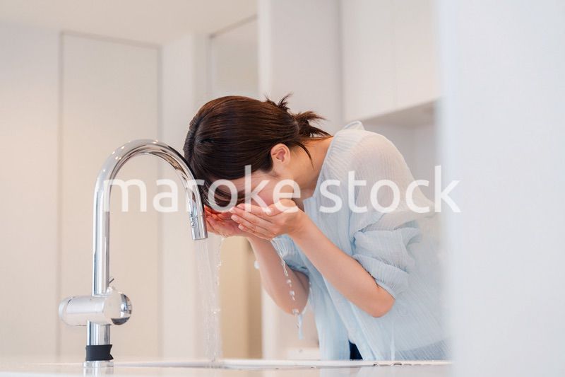 家で洗顔をする若い女性