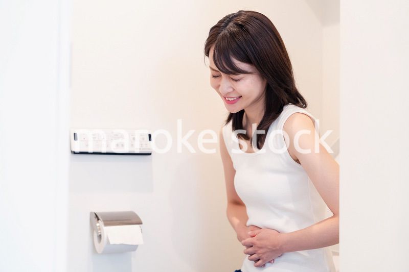 トイレでひどい腹痛に苦しむ若い女性