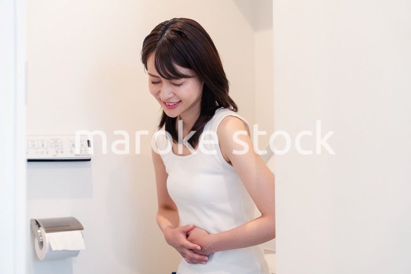 トイレでひどい腹痛に苦しむ若い女性