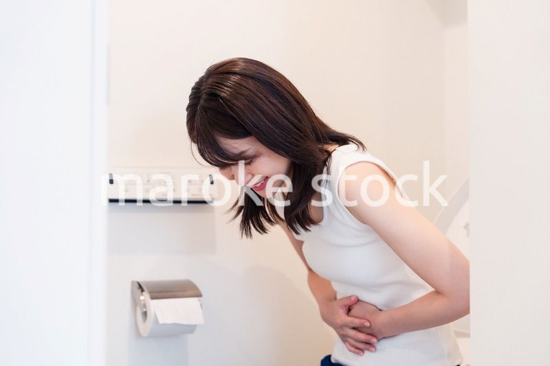 トイレでひどい腹痛に苦しむ若い女性