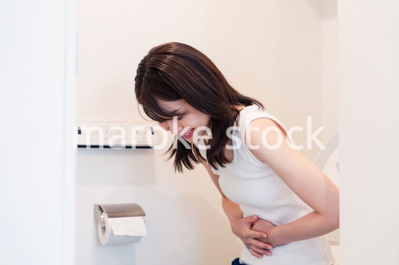 トイレでひどい腹痛に苦しむ若い女性