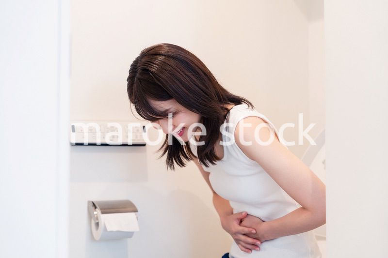 トイレでひどい腹痛に苦しむ若い女性