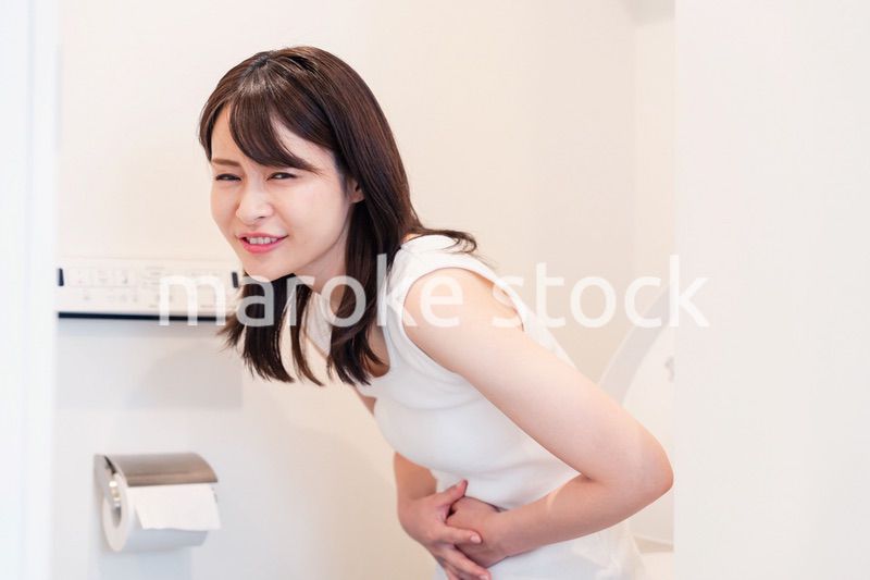 トイレでひどい腹痛に苦しむ若い女性