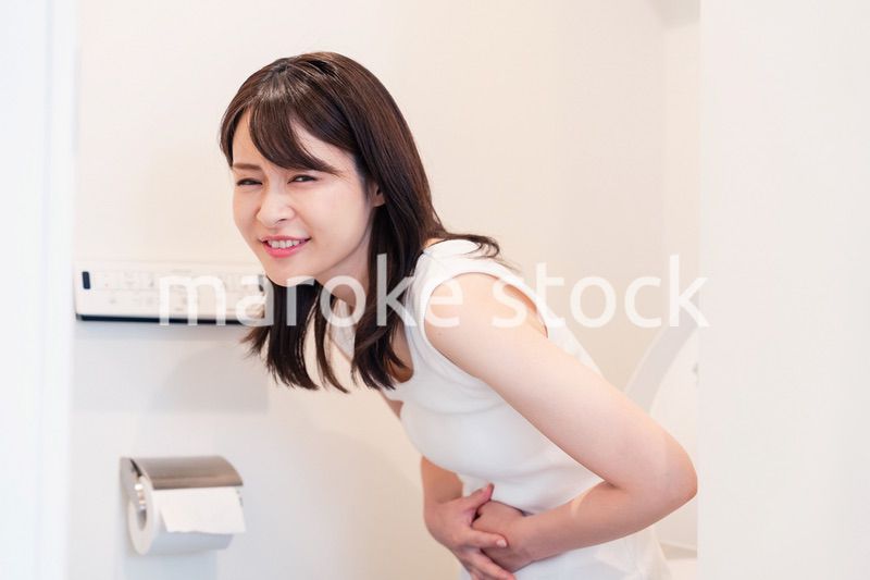 トイレでひどい腹痛に苦しむ若い女性