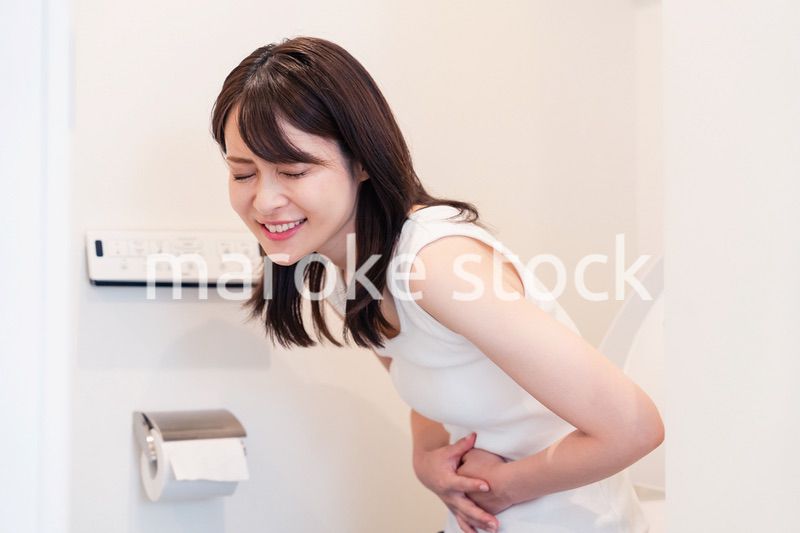 トイレでひどい腹痛に苦しむ若い女性