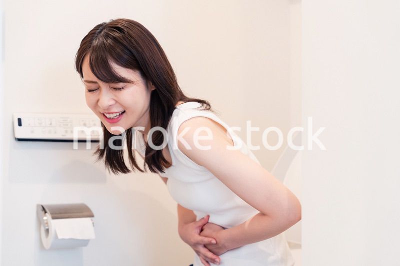 トイレでひどい腹痛に苦しむ若い女性