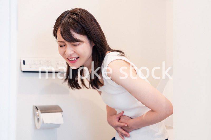 トイレでひどい腹痛に苦しむ若い女性