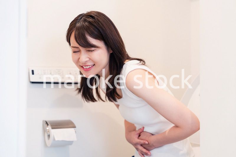 トイレでひどい腹痛に苦しむ若い女性