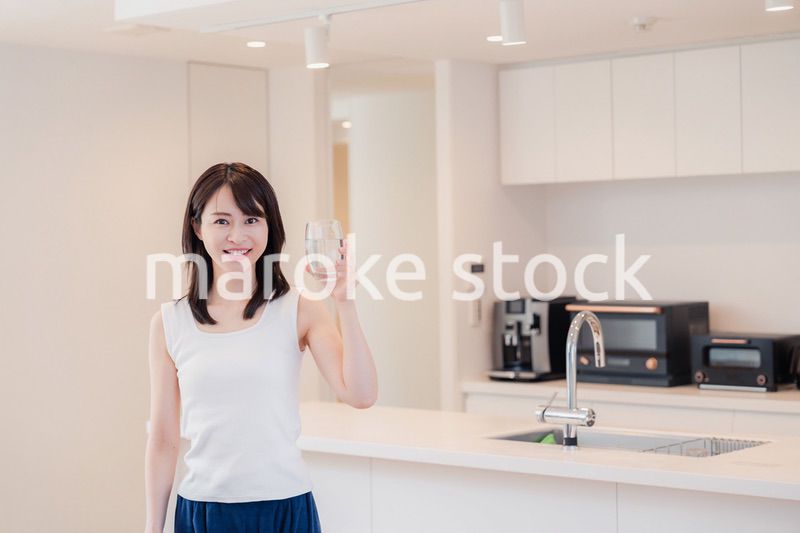 家で水を飲む若い女性