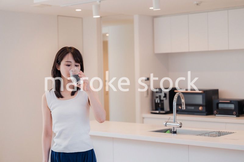 家で水を飲む若い女性