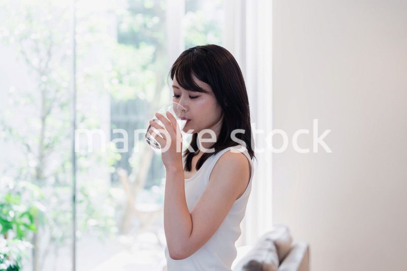 家で水を飲む若い女性