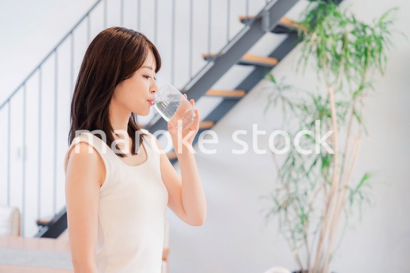 家で水を飲む若い女性
