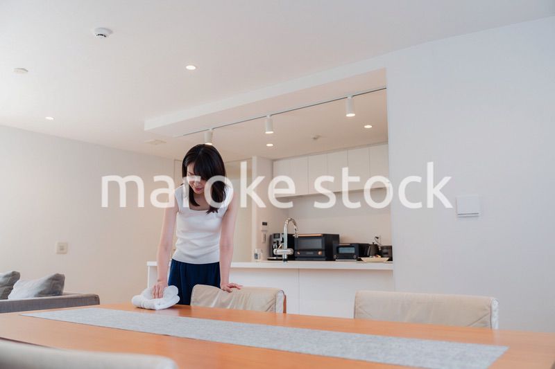 ダイニングテーブルを拭く若い女性