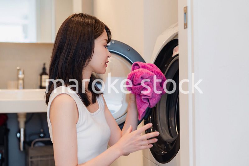 ドラム式洗濯機を使う若い女性