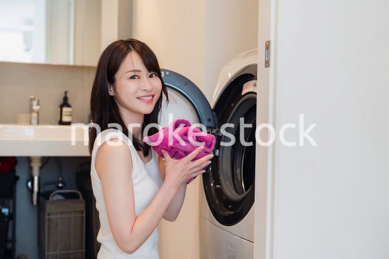 ドラム式洗濯機を使う若い女性