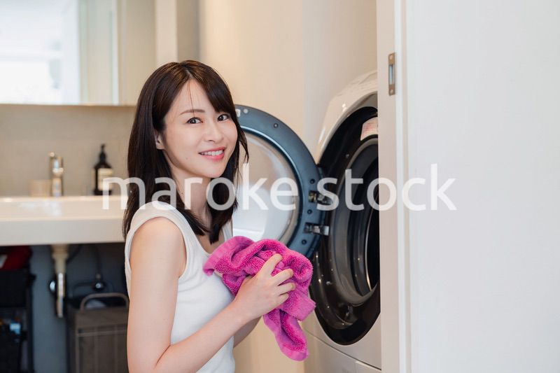ドラム式洗濯機を使う若い女性