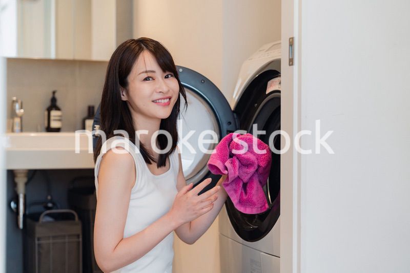 ドラム式洗濯機を使う若い女性