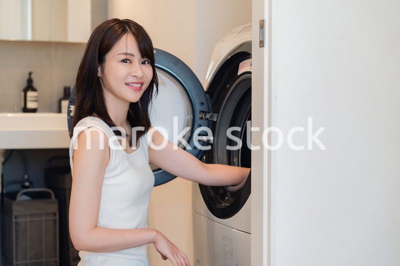 ドラム式洗濯機を使う若い女性