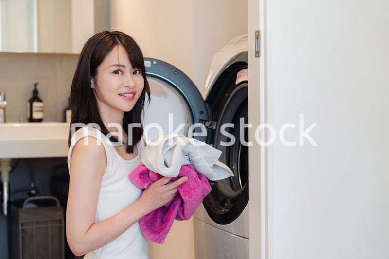 ドラム式洗濯機を使う若い女性