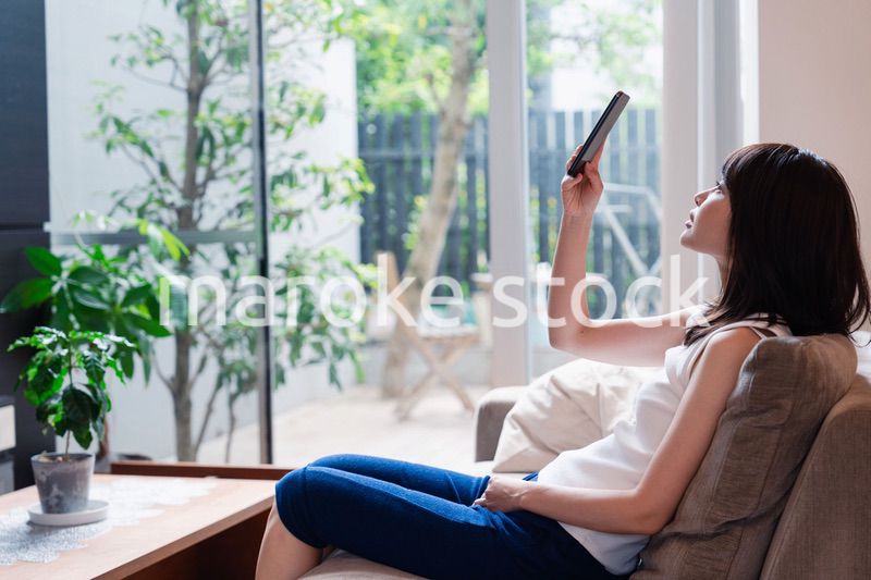 ソファでリラックスしてスマホを使う若い女性