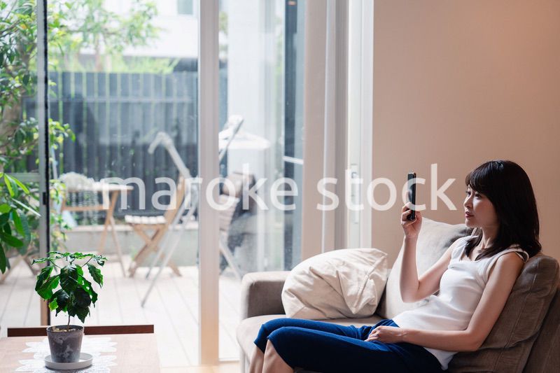 ソファでリラックスしてスマホを使う若い女性